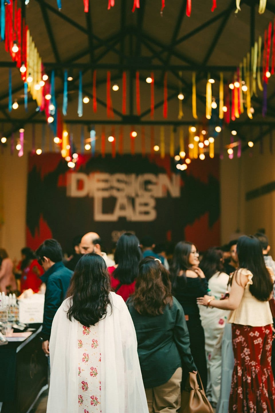 People mingling at a festive event in front of a Design Lab sign.