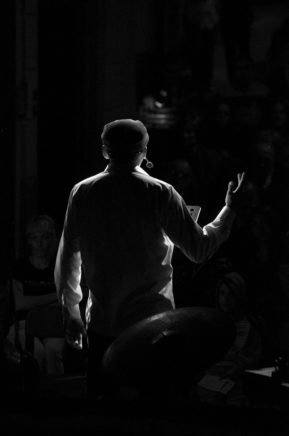Speaker on a dark stage gesturing to an audience.